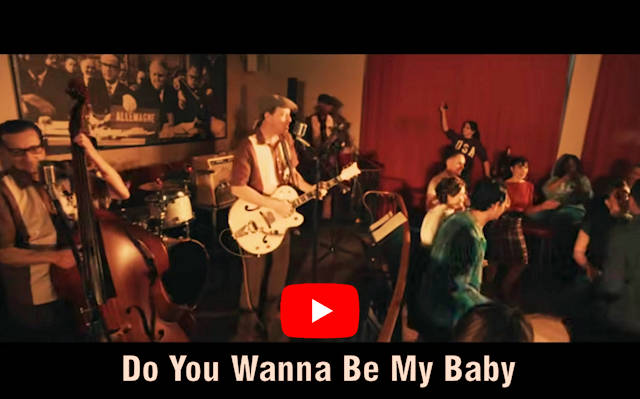 One can see dancers dancing in front of a stage with a band. Below it is the song title 'Do You Wanna Be My Baby' with the YouTube logo above it.